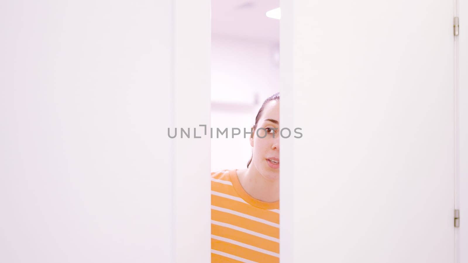 Woman peeping surreptitiously looking through a half-open door by ivanmoreno