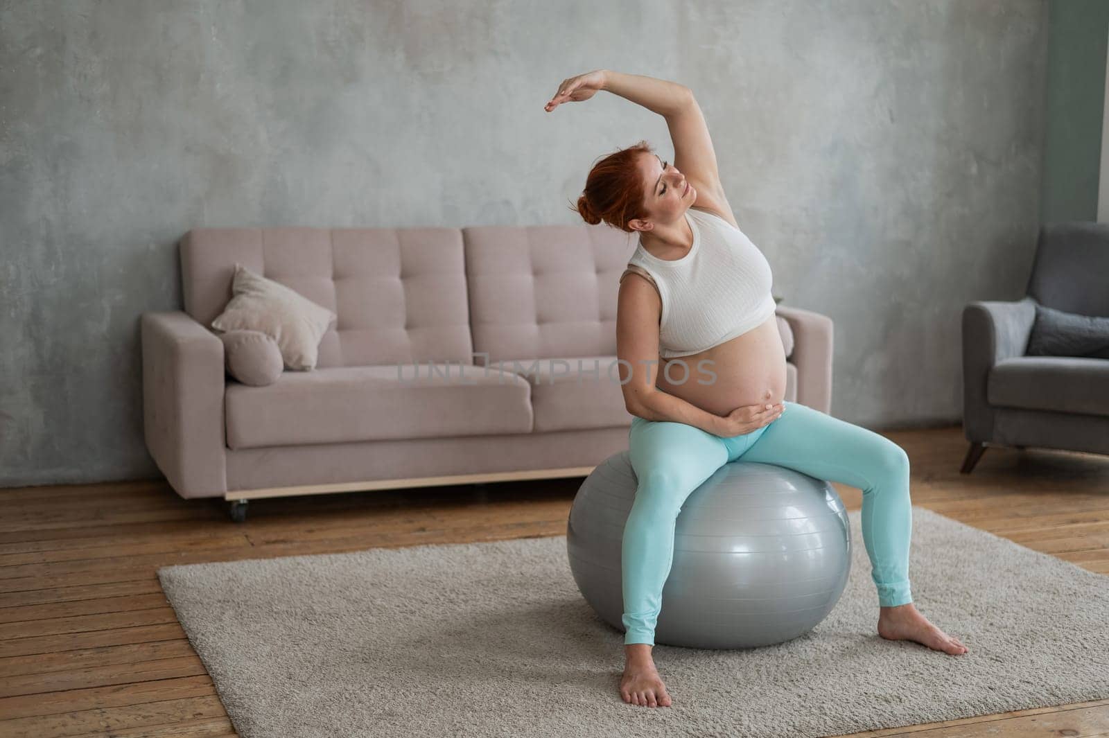 Pregnant woman doing lateral bends on a fitball at home. by mrwed54