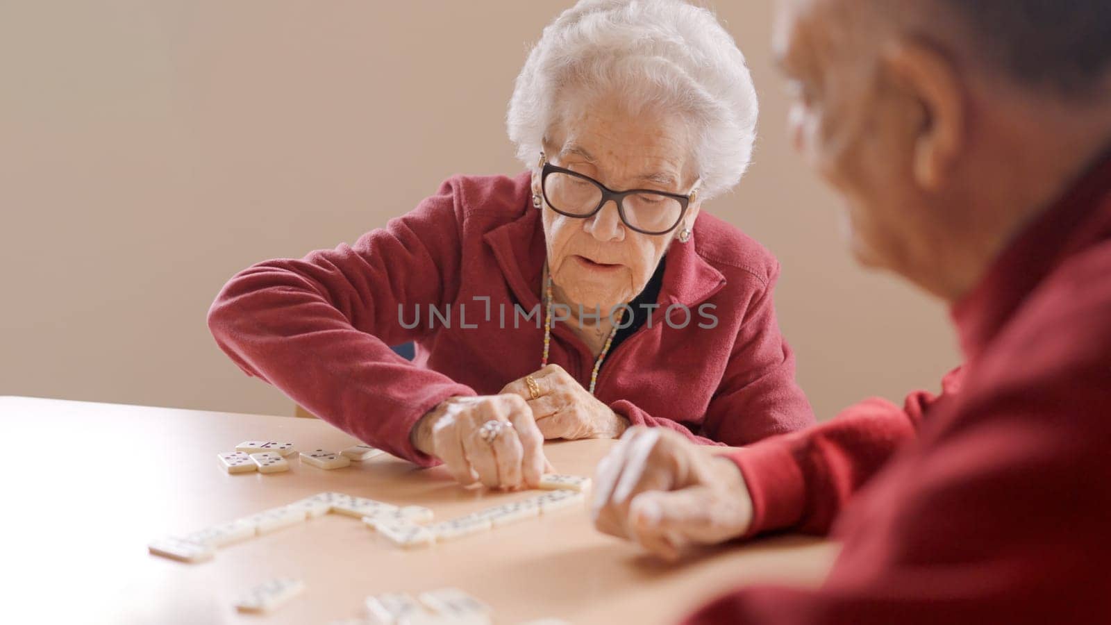 Senior people playing dominoes patiently in nursing home by ivanmoreno