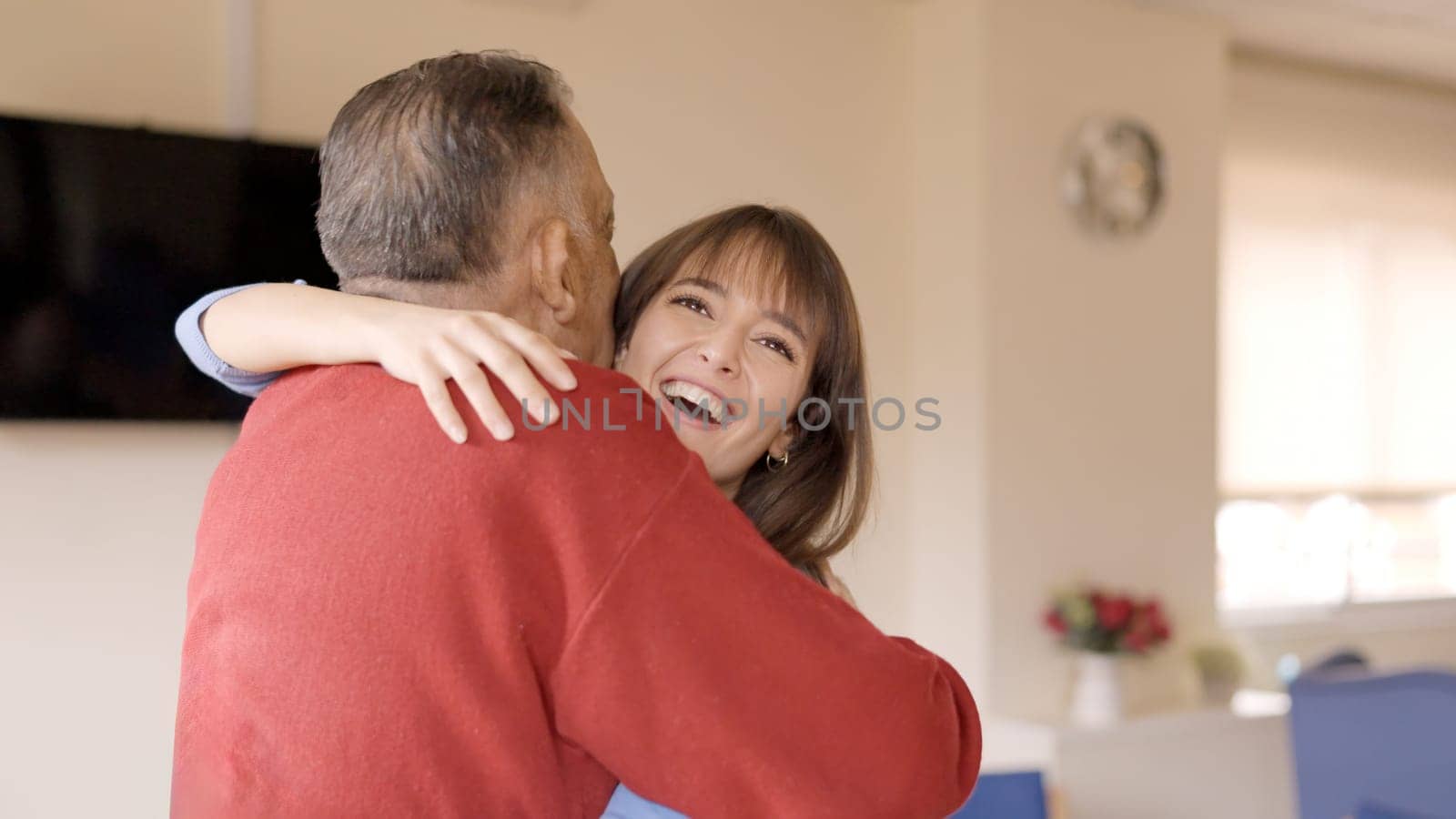 An adult granddaughter embracing her grandfather visiting him in a geriatric