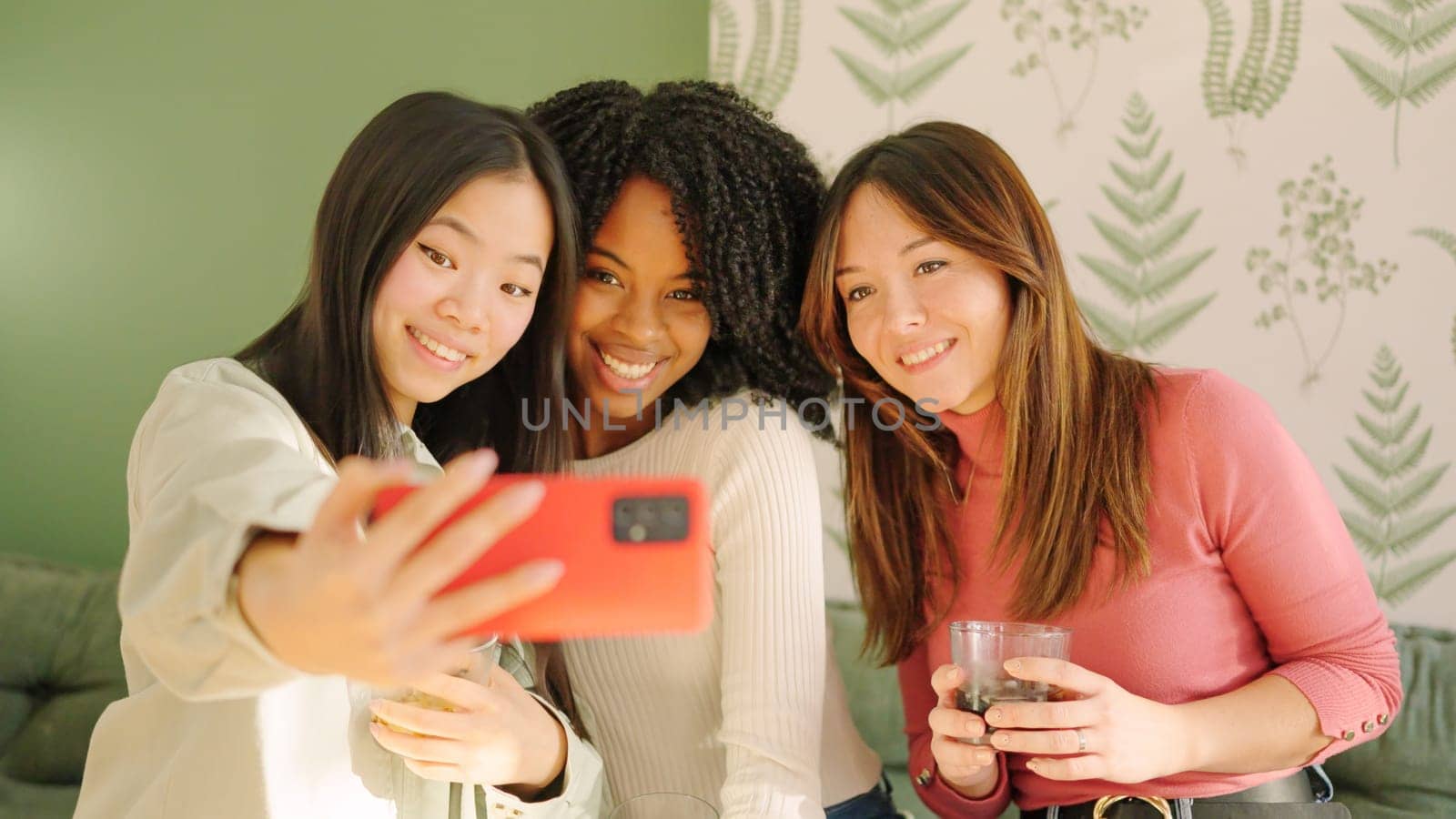 Multi-ethnic friends smiling taking a selfie indoors by ivanmoreno