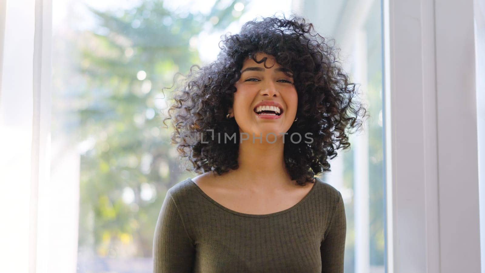 Beauty african woman with curly hair laughing at camera at home