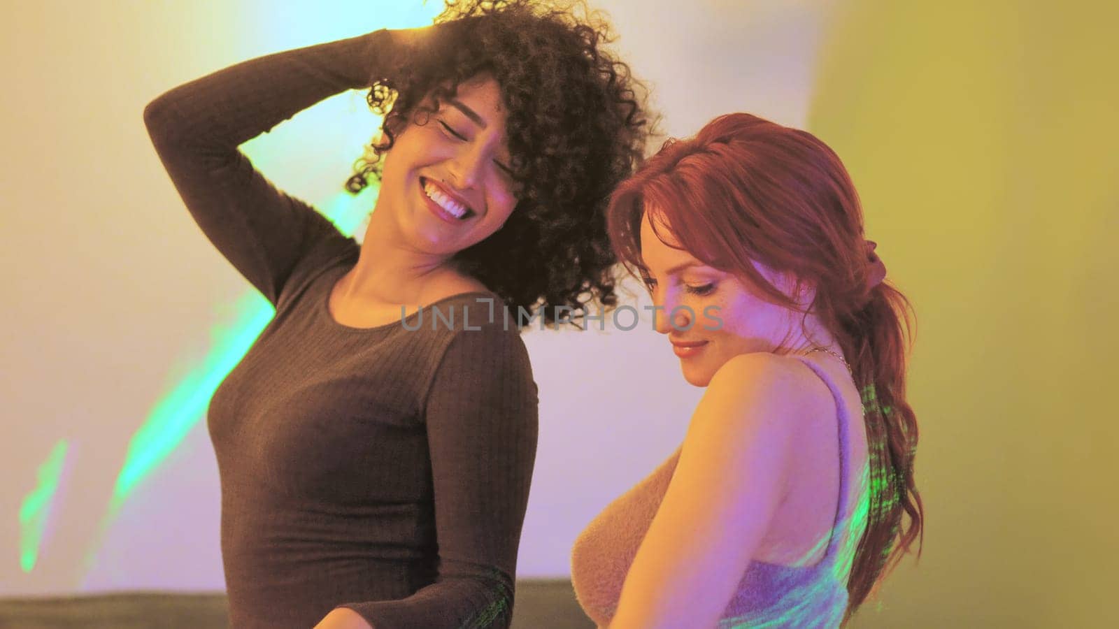 Two multi-ethnic sensual women dancing together in a home party
