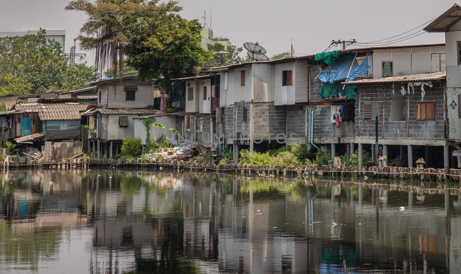 Bangkok, Thailand - Apr 20, 2024 - In slum area, the houses are old along the Khlong Phra Khanong. Broken houses are beside the Canal with dirty water. Bad pollution problem, Space for text, Selective focus.