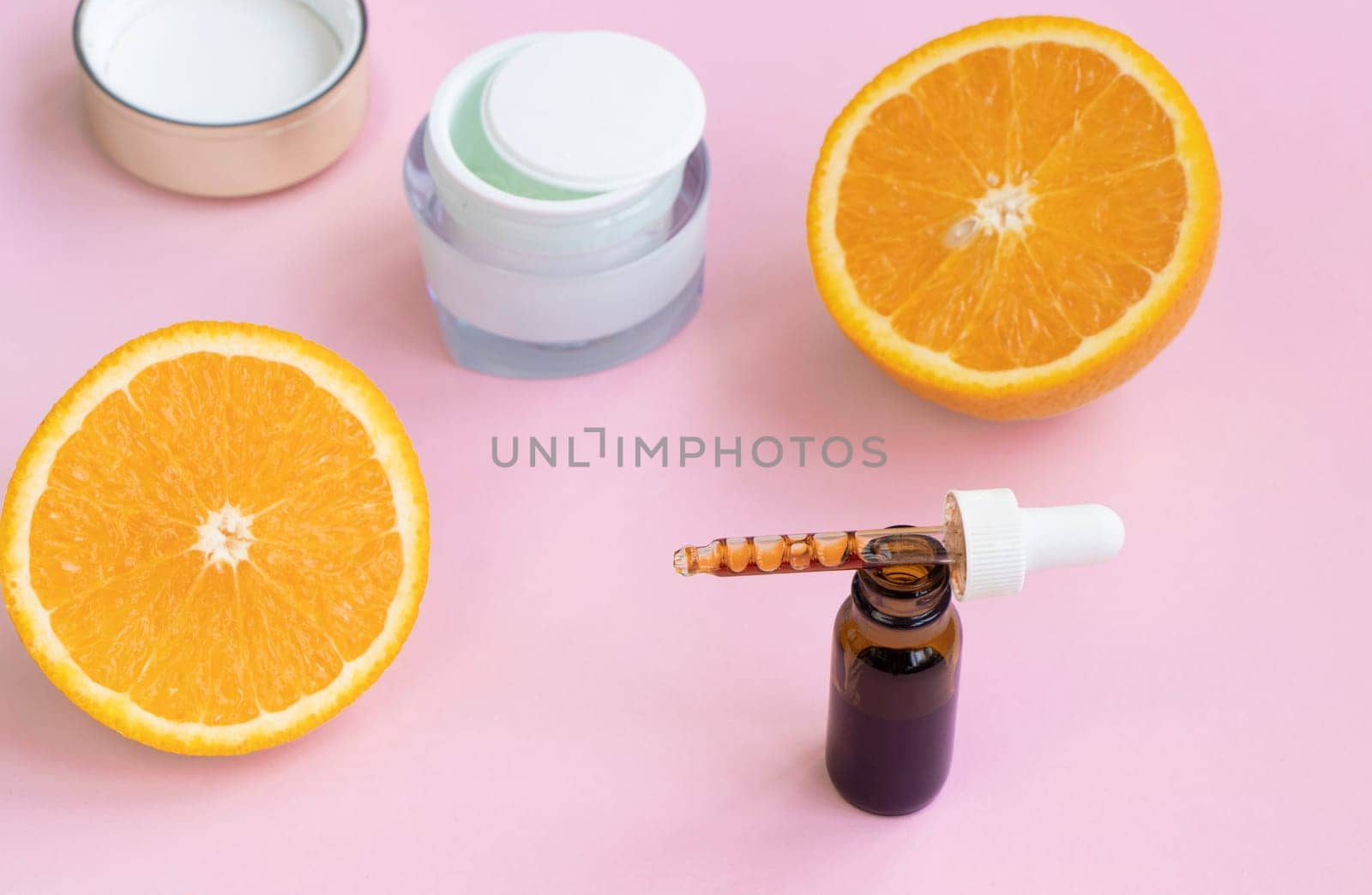 face serum in a pipette, cream and citrus fruits on a pink background. Antioxidants and vitamin c concept in skin care. High quality photo