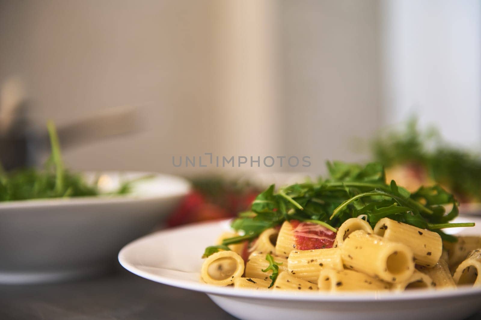 Classic Italian cuisine dish. Pasta penne with tomatoes, arugula leaves and parmesan cheese. Copy advertising space. Food background. Classic Italian cuisine dish. by artgf