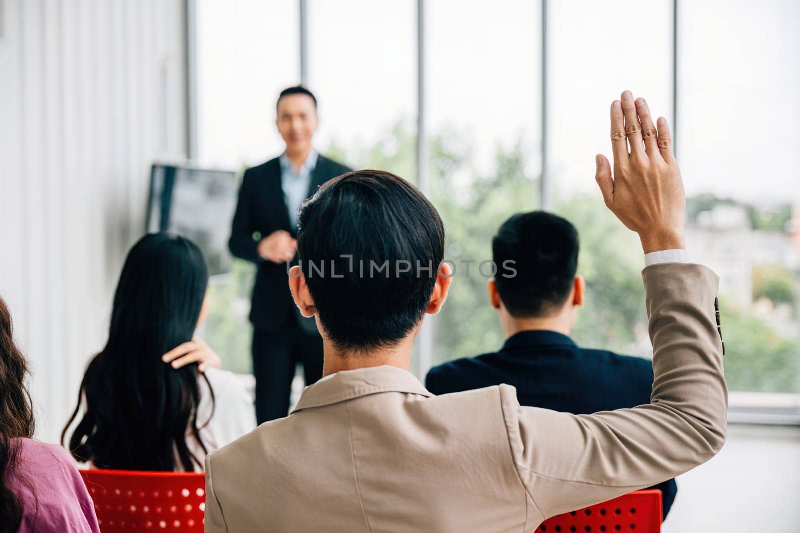 At a conference, hands are raised for questions, underlining the active participation of the audience. A diverse group collaborates in a workshop or seminar, emphasizing teamwork and discussion.