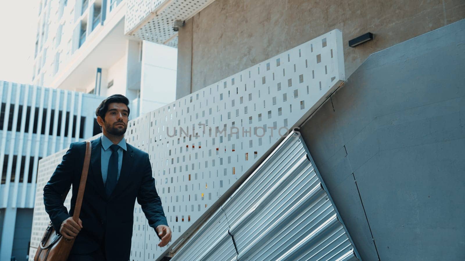 Smart business man walking up the stairs with confident near building. Skilled project manger walking on stairs seeking for job, going for new job near at modern skyscraper. Copy space. Exultant.