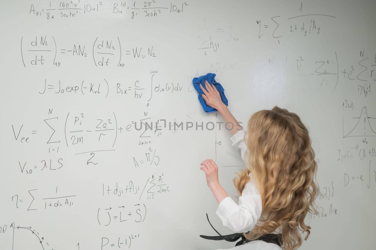 Caucasian woman erasing formulas from white board