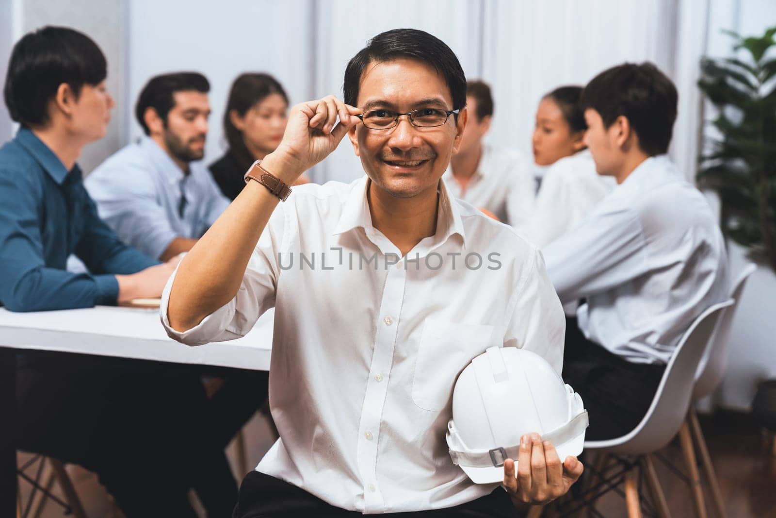 Engineer team leader portrait with diverse group of civil engineer and client working together on architectural project, reviewing construction plan and building blueprint at meeting table. Prudent