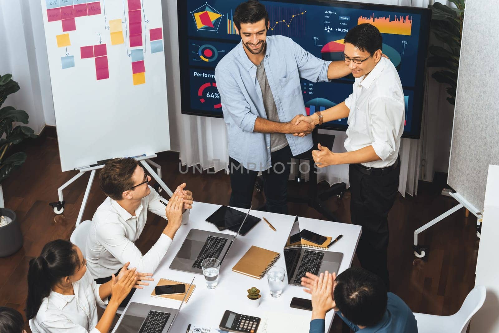 Analyst team leader shake hand with his colleague after successful data analysis meeting using FIntech software power with business intelligence or BI dashboard. Prudent