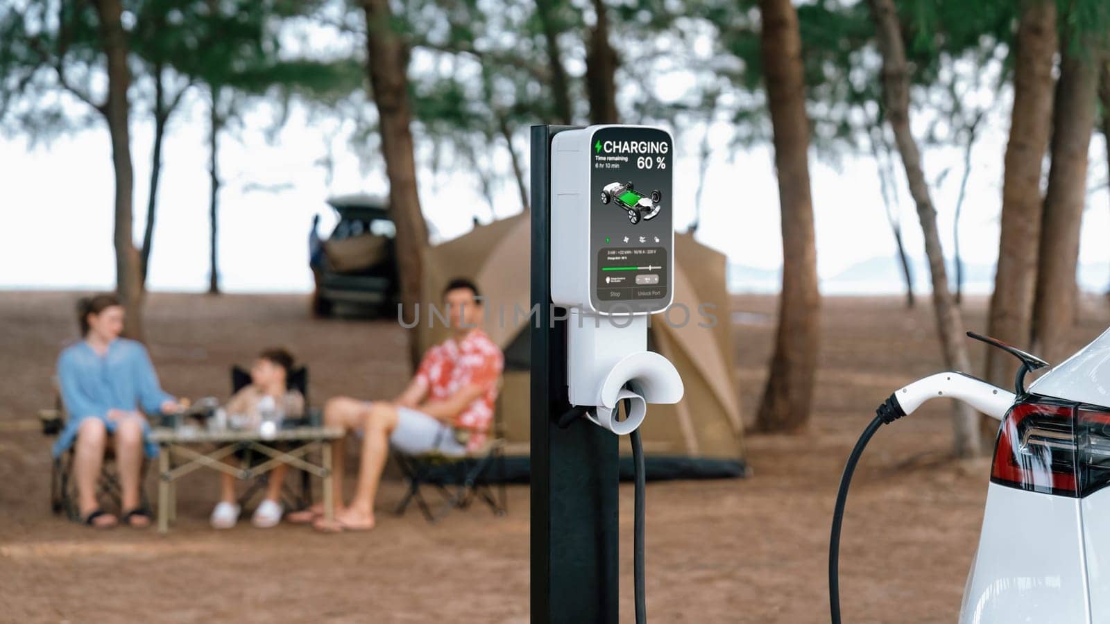 EV car charging with blurred family enjoying the seascape background. Perpetual by biancoblue