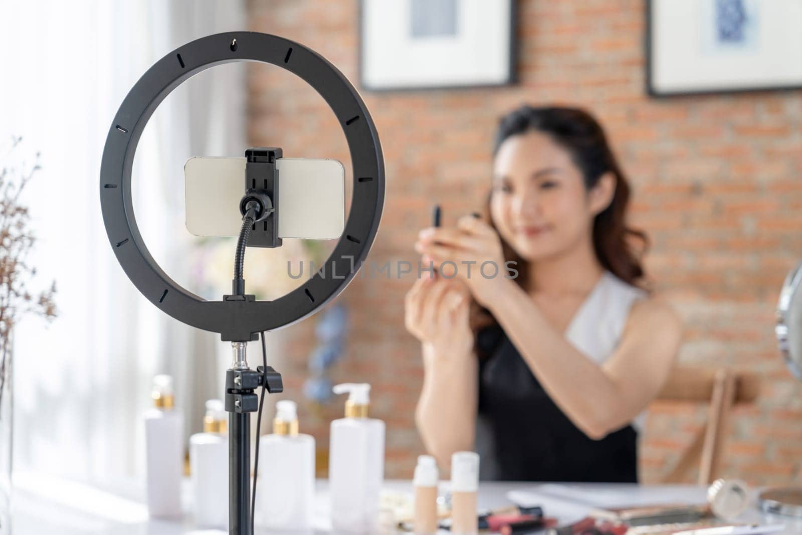 Woman influencer shoot live streaming vlog video review makeup uttermost social media or blog. Happy young girl with cosmetics studio lighting for marketing recording session broadcasting online.