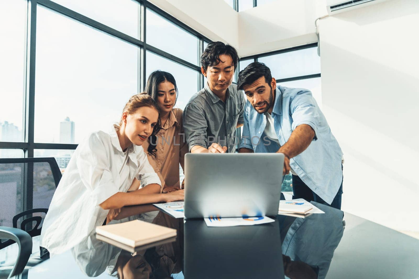 Asian project manager uses laptop displayed data analysis while professional business team brainstorming marketing idea at business meeting. Working together,sharing idea, planing strategy. Tracery.