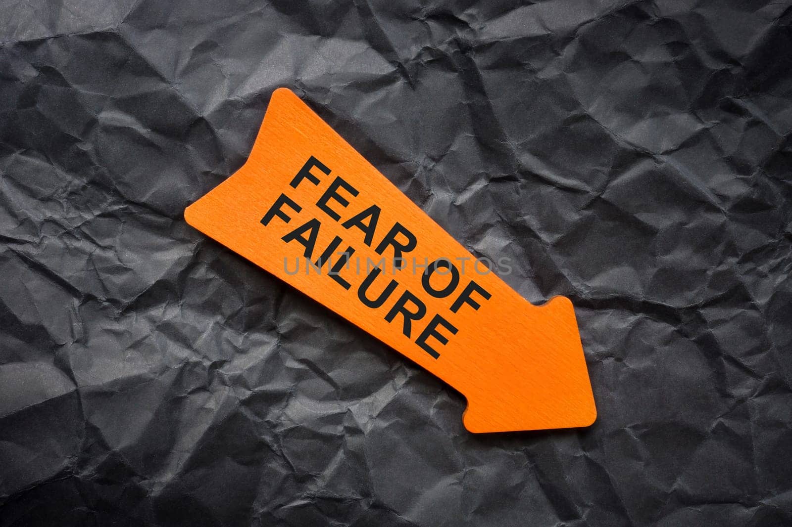 Fear of failure abstract. Crumpled paper and orange arrow. by designer491