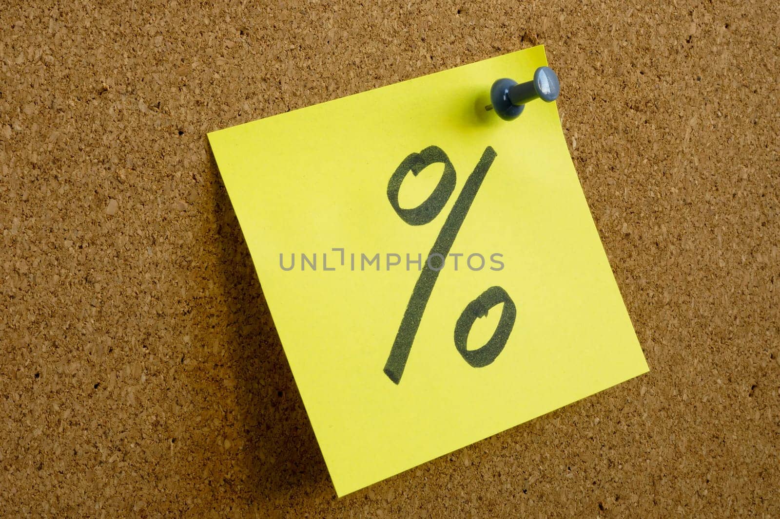 A note with a percent sign as a symbol of profit is pinned to an office board. by designer491