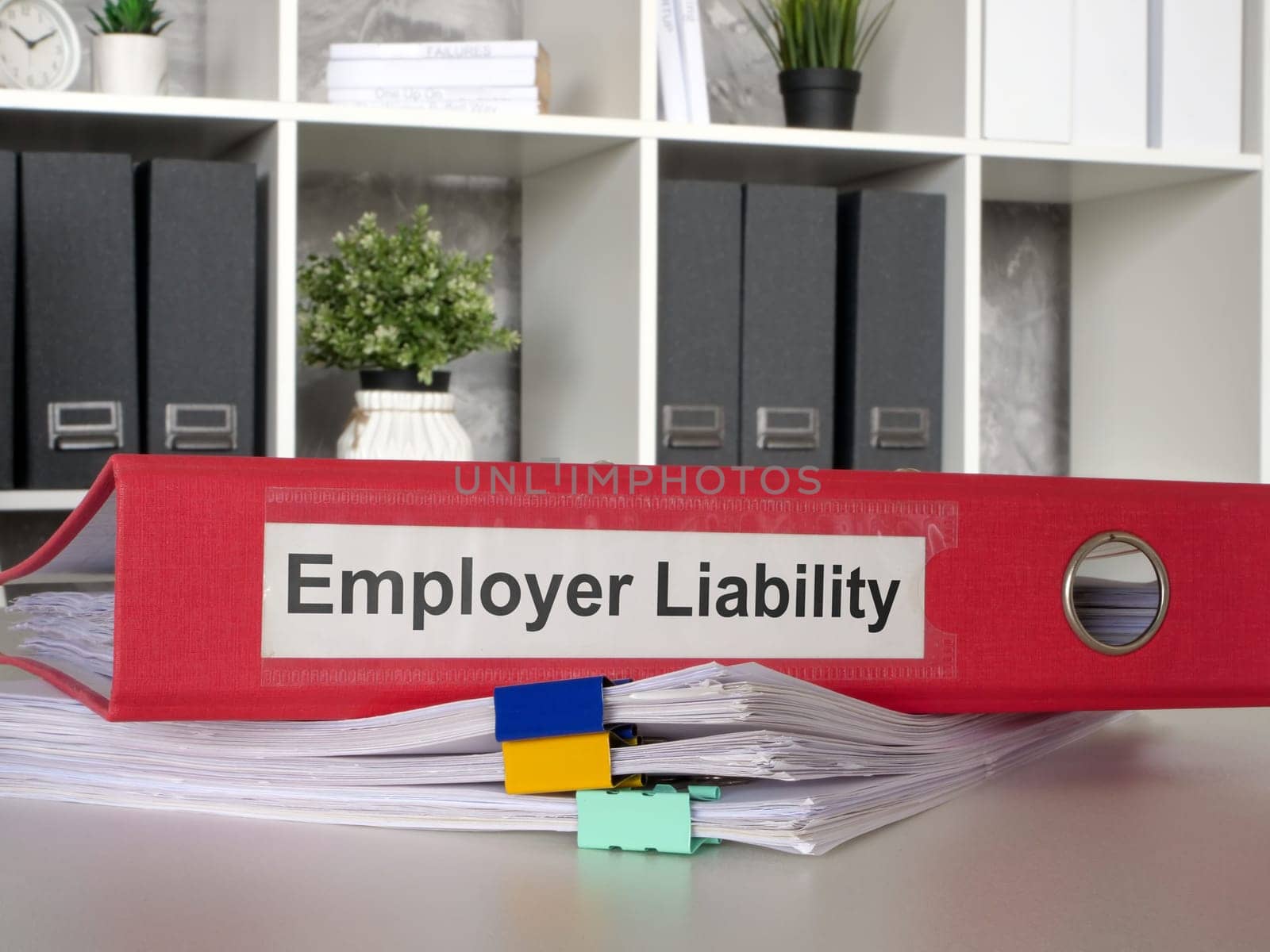 The folder Employer liability lies on a stack of papers. by designer491