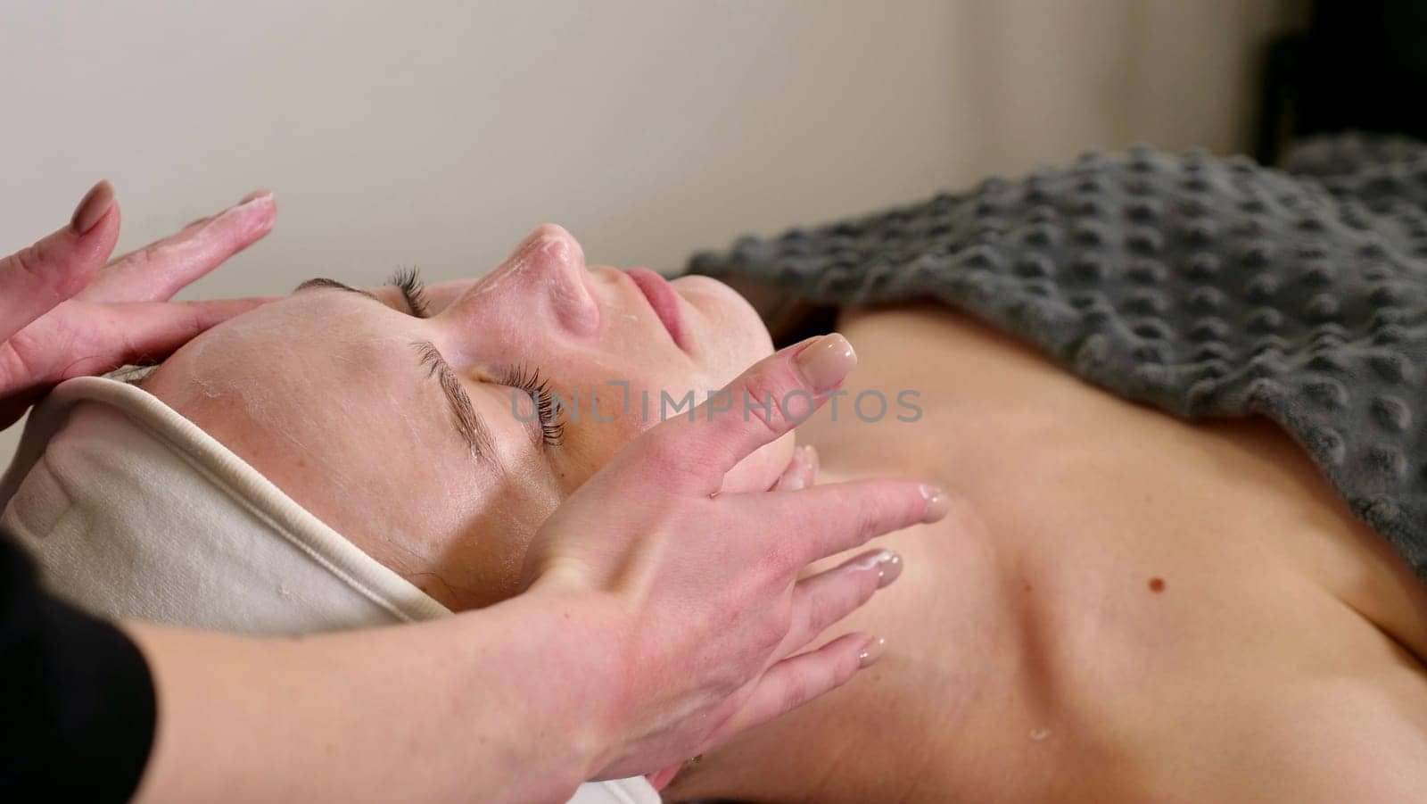 An experienced cosmetologist massage therapist performs a relaxing facial massage for the client to relieve tension, promoting deep relaxation and hydration, leaving your skin refreshed and radiant.