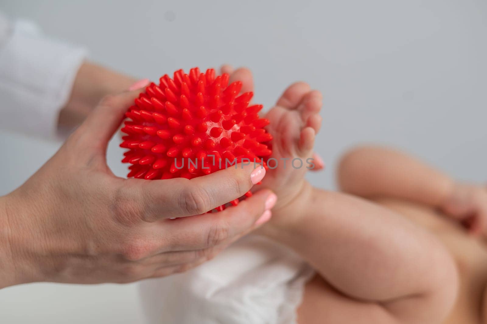 A doctor massages a baby's foot using a spiked ball