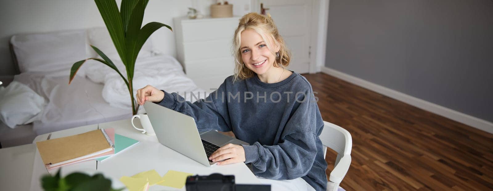 Portrait of young beautiful woman, social media influencer, recording video tutorial, lifestyle vlog, creating content in her room using digital camera.