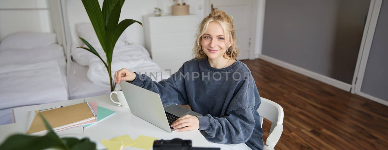 Portrait of woman sitting at desk with laptop, recording video of herself on laptop, making lifestyle video for social media account by Benzoix