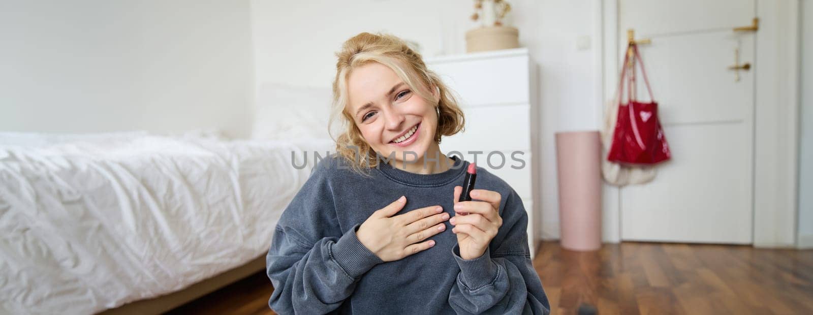 Portrait of cute, charismatic beauty blogger, woman sits in a room with lipstick in hand, talking about makeup, chatting with followers, recording online stream on social media app by Benzoix