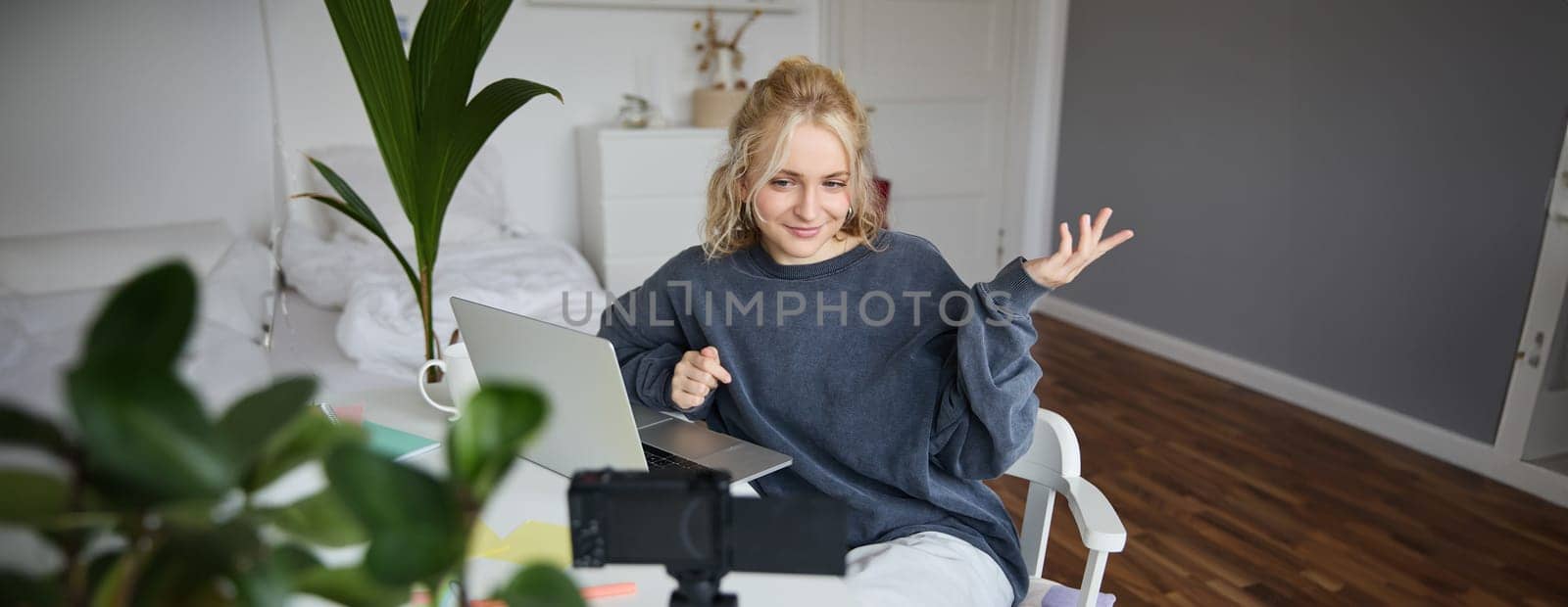 Portrait of young woman, lifestyle blogger, recording vlog video about her life and daily routine, sitting in front of laptop, talking to followers, sitting in her room by Benzoix