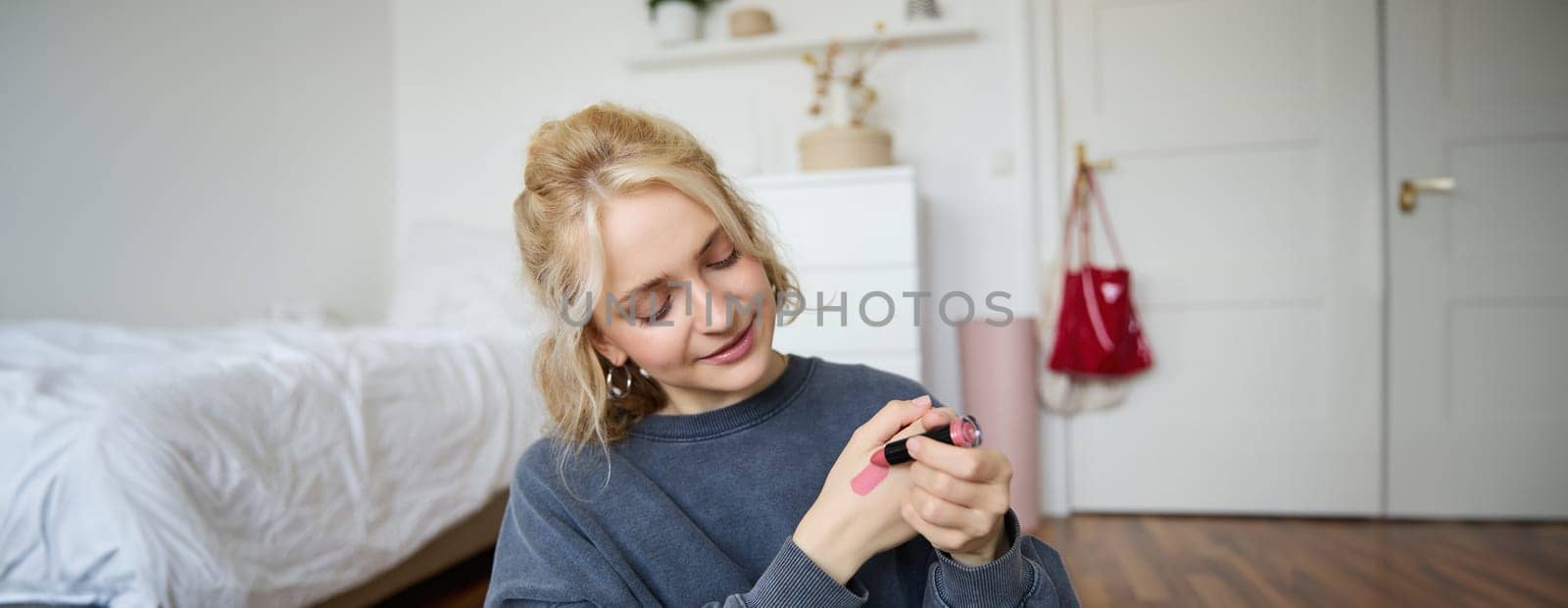 Portrait of young makeup artist, beauty blogger showing new lipstick, recording video in her room, smiling and expressing positivity by Benzoix