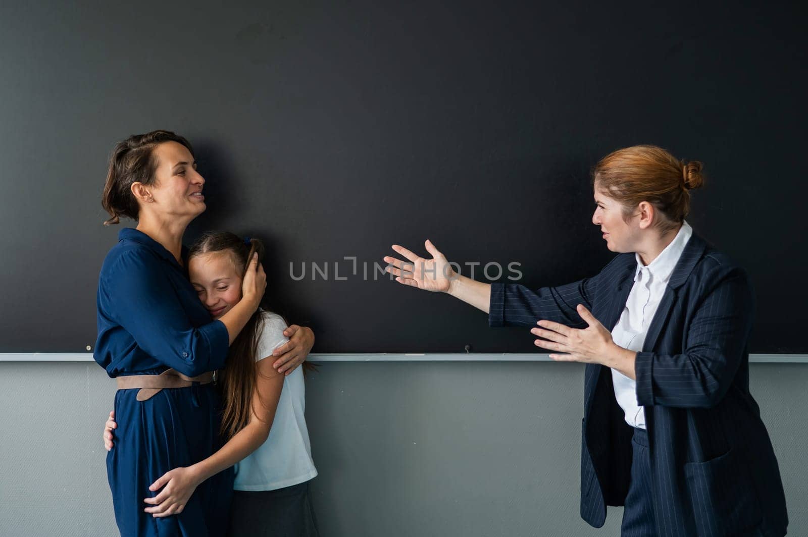 The teacher screams at the schoolgirl and her mother standing at the blackboard. by mrwed54