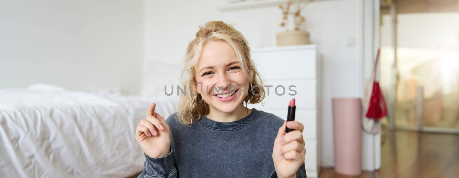 Portrait of cute, charismatic beauty blogger, woman sits in a room with lipstick in hand, talking about makeup, chatting with followers, recording online stream on social media app by Benzoix