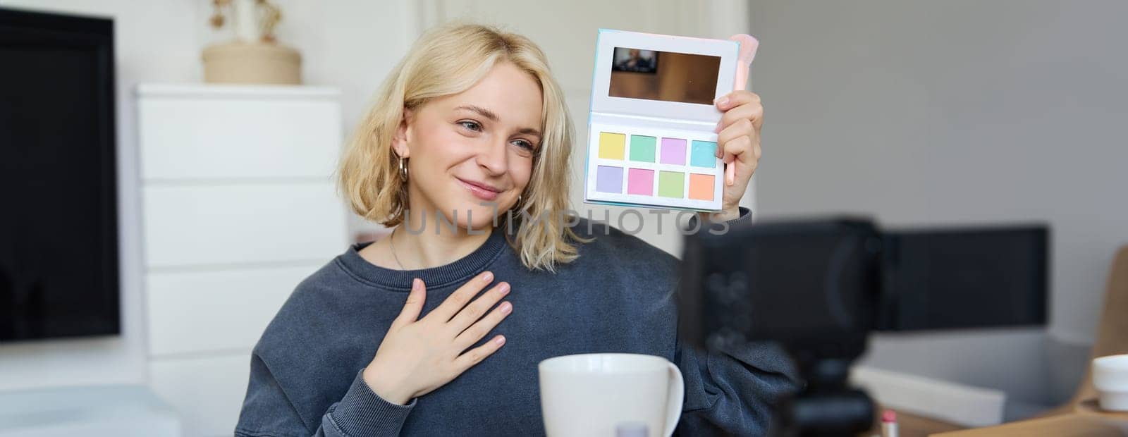 Lifestyle blogger, records video in her room, has a camera on coffee table, shows eyeshadow palette to her followers, does makeup tutorial, vlogger working indoors, creates content for social media by Benzoix