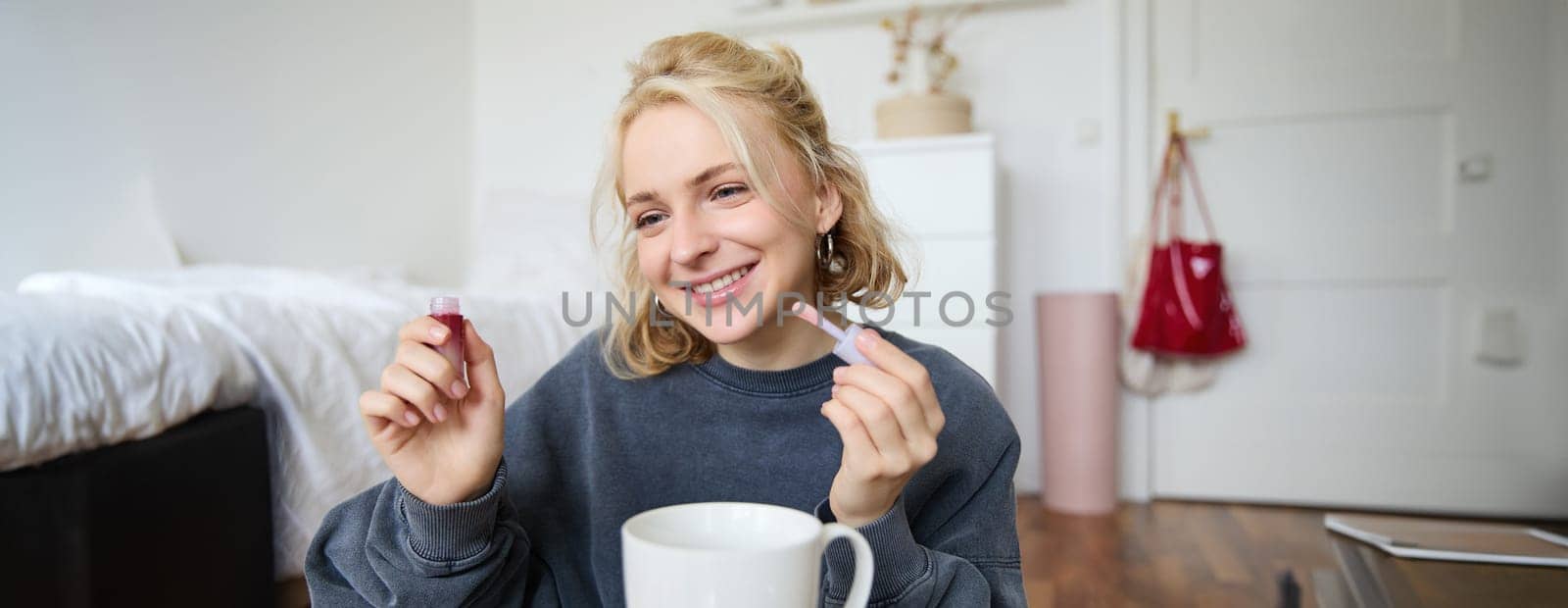 Portrait of smiling charismatic woman, puts on lip gloss, drinks tea, records video on digital camera, beauty content for social media account.