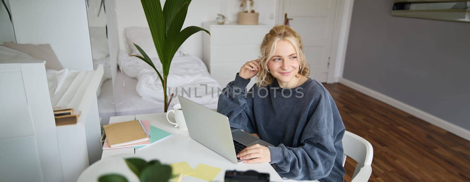 Portrait of woman sitting at desk with laptop, recording video of herself on laptop, making lifestyle video for social media account by Benzoix