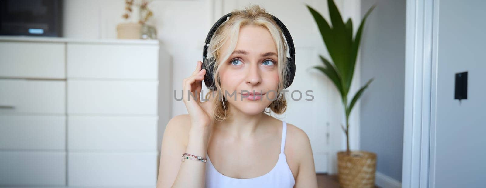 Concept of people and lifestyle, Close up of beautiful blond woman in wireless headphones, listens to music, enjoys good quality sound in new earphones by Benzoix