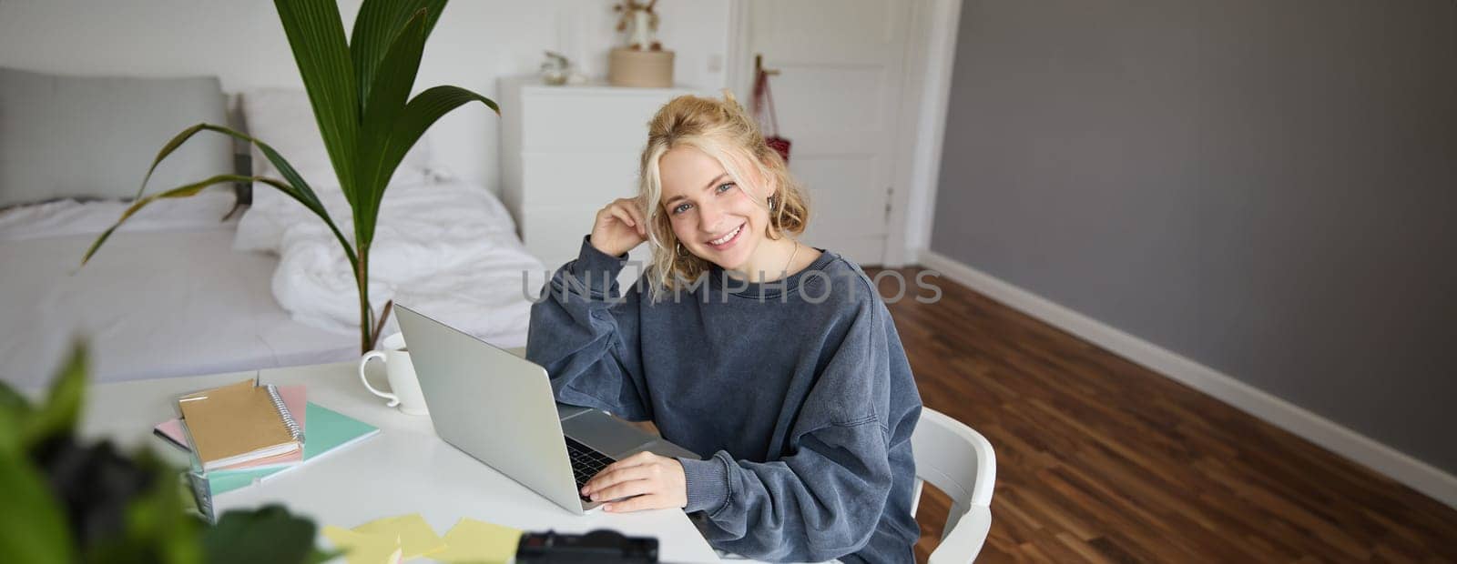 Portrait of young woman, lifestyle blogger, recording vlog video about her life and daily routine, sitting in front of laptop, talking to followers, sitting in her room.