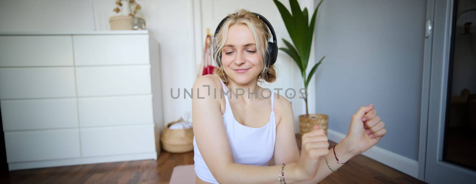 Close up of athletic young woman, cute female model in wireless headphones, dancing to favorite song, listens to music in earphones.