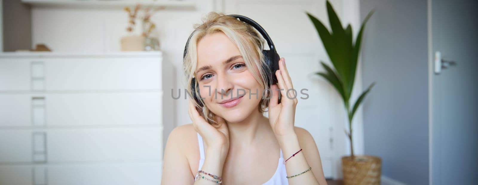 Concept of people and lifestyle, Close up of beautiful blond woman in wireless headphones, listens to music, enjoys good quality sound in new earphones by Benzoix