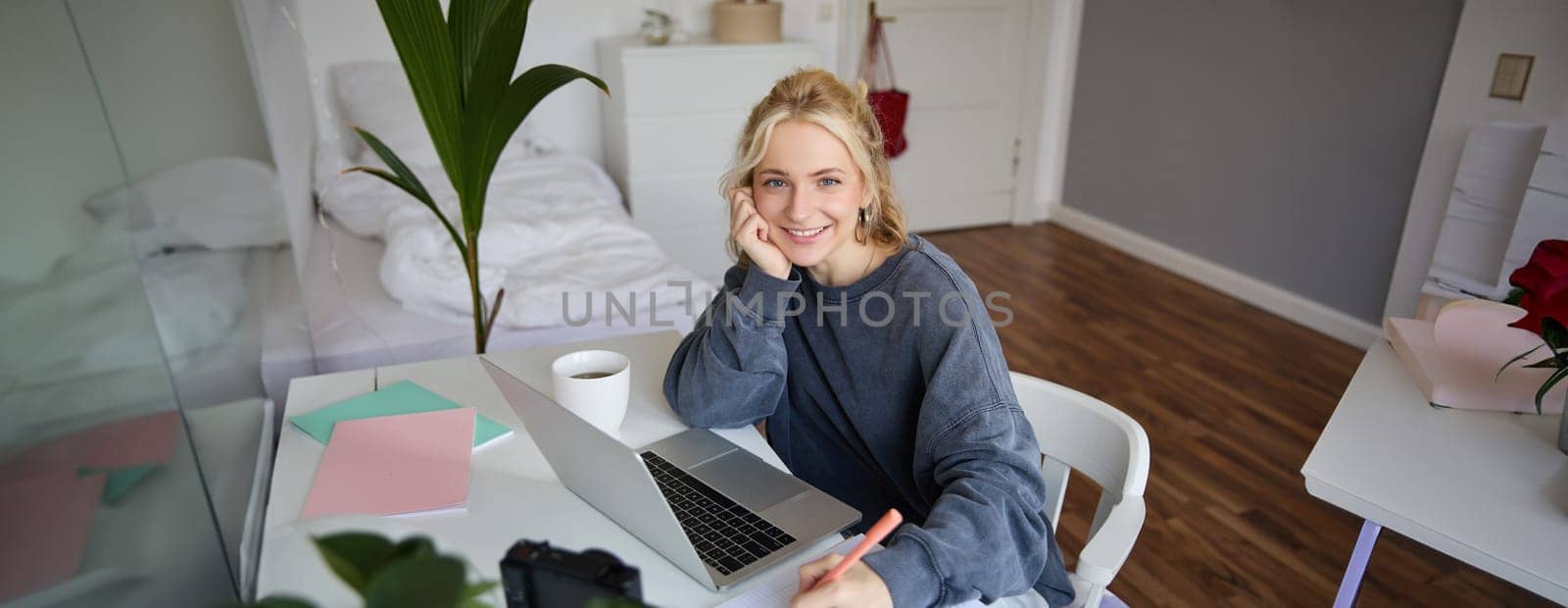 Portrait of young woman distance learning, working from home with laptop, making notes, student studying on remote, doing online course.