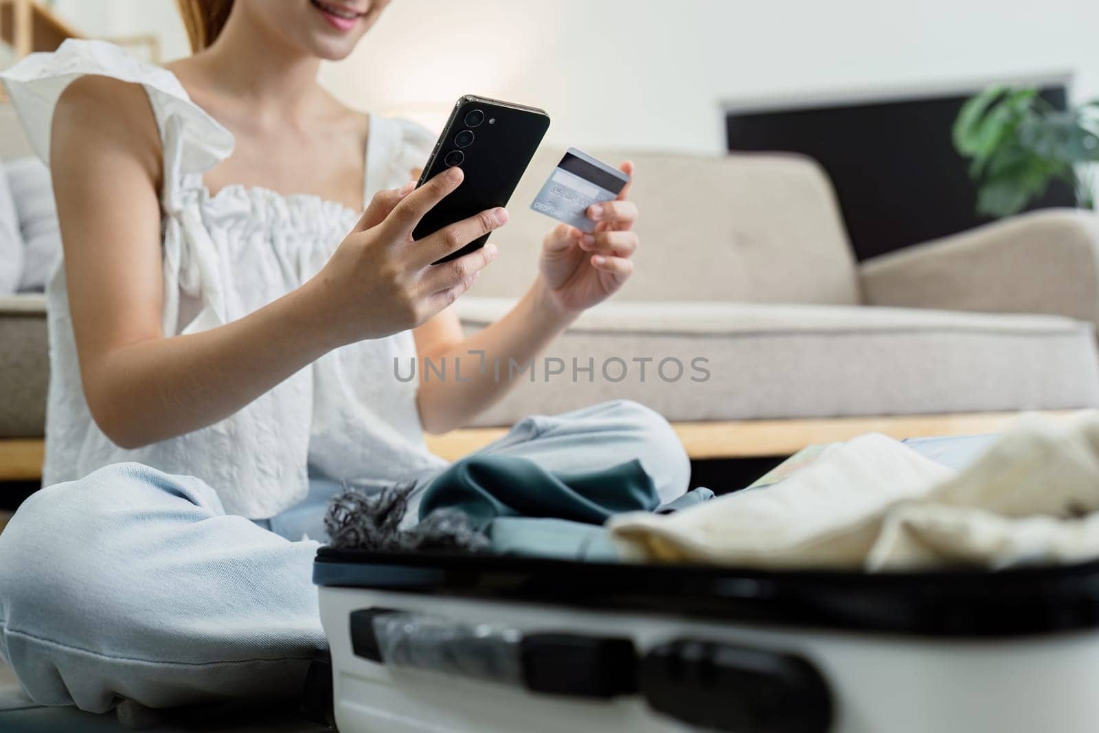 Happy young woman with credit card booking vacation at travel agency or making hotel reservation online.