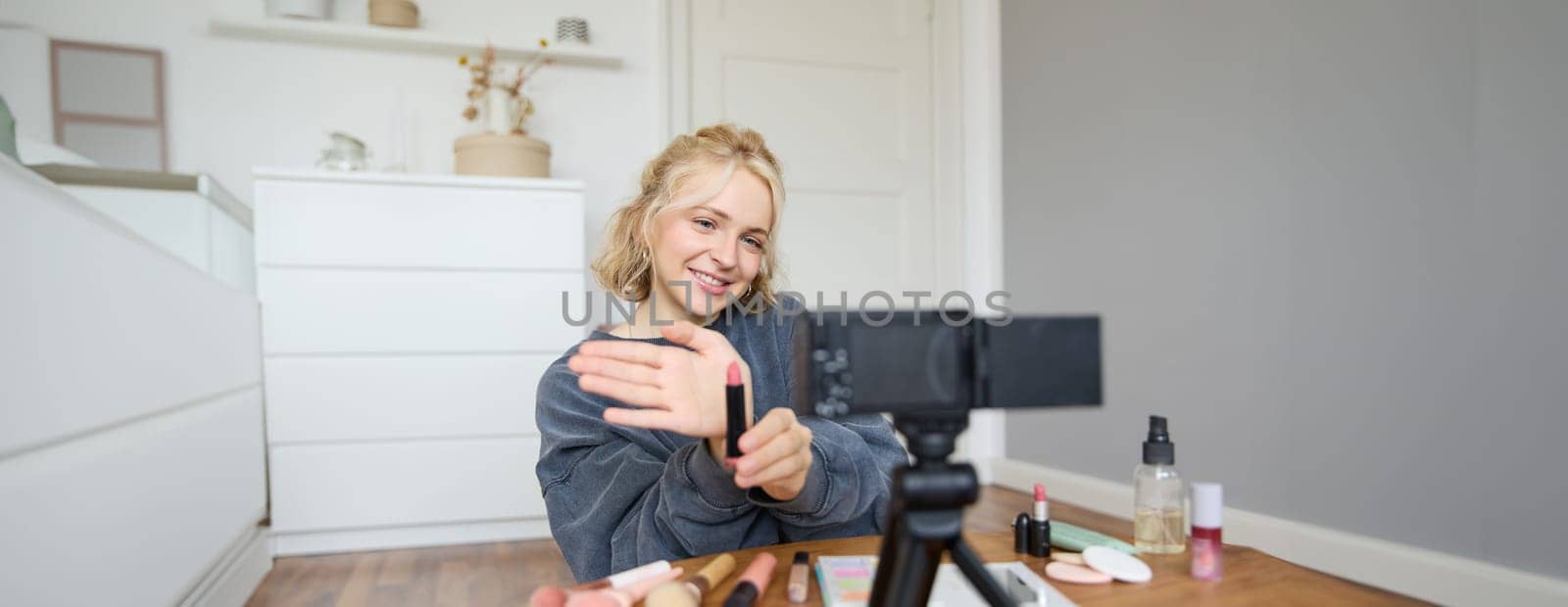 Portrait of young content maker, woman blogger recording a video on digital camera, showing lipstick colour to her followers, creating lifestyle vlog for social media account by Benzoix