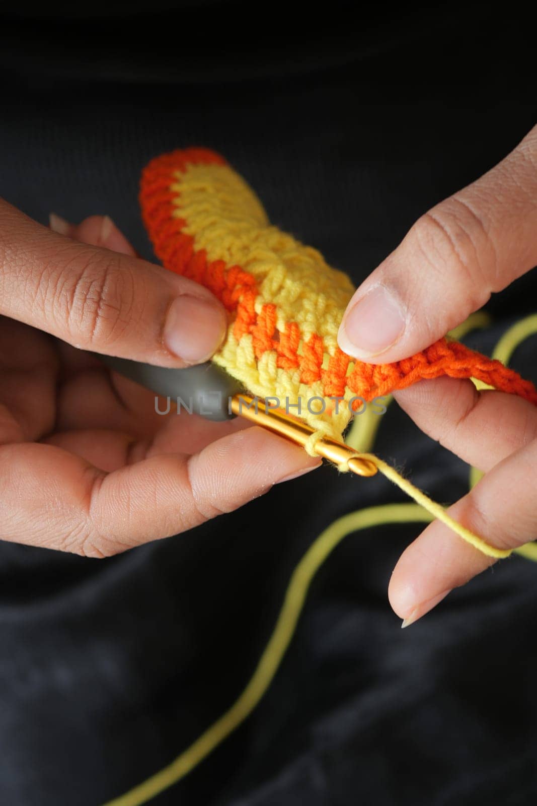 Hand close up crocheting with a hook, wool yarn, creative craft.