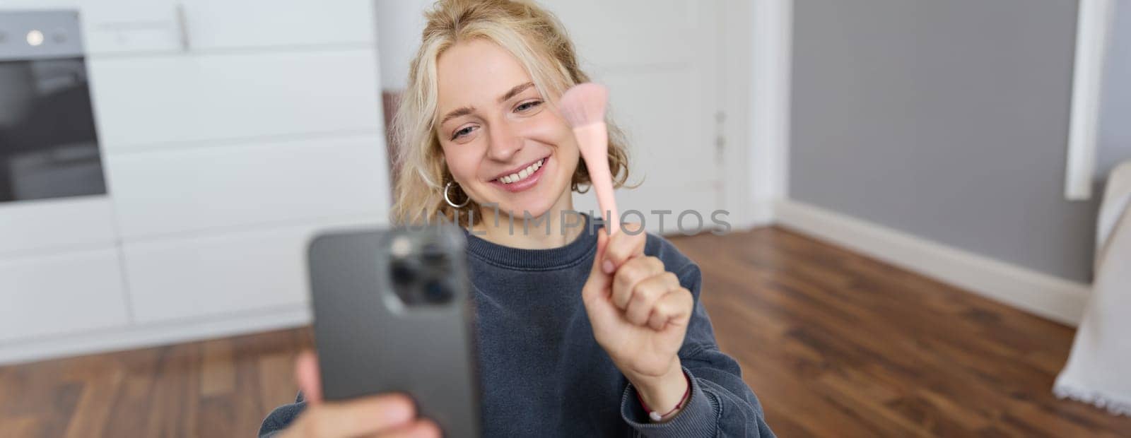 Portrait of young woman, social media influencer, taking selfies in her room, sitting on floor, holding smartphone and posing for a photo by Benzoix