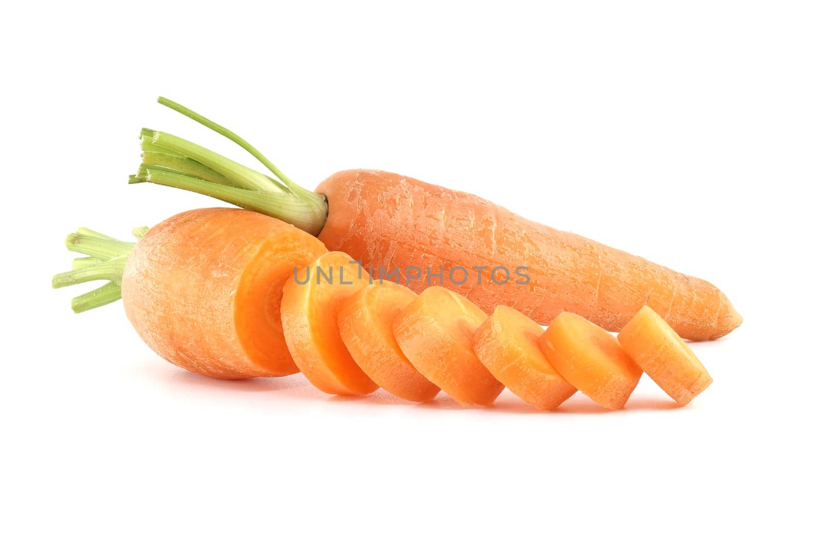 Whole carrot alongside its sliced pieces over white background by NetPix