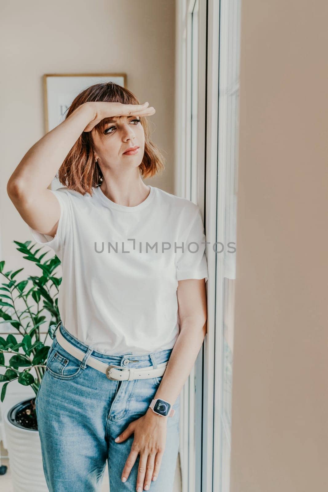 Office window woman. Business woman standing in the office with her arms crossed near the window. Dressed in a white T-shirt and jeans