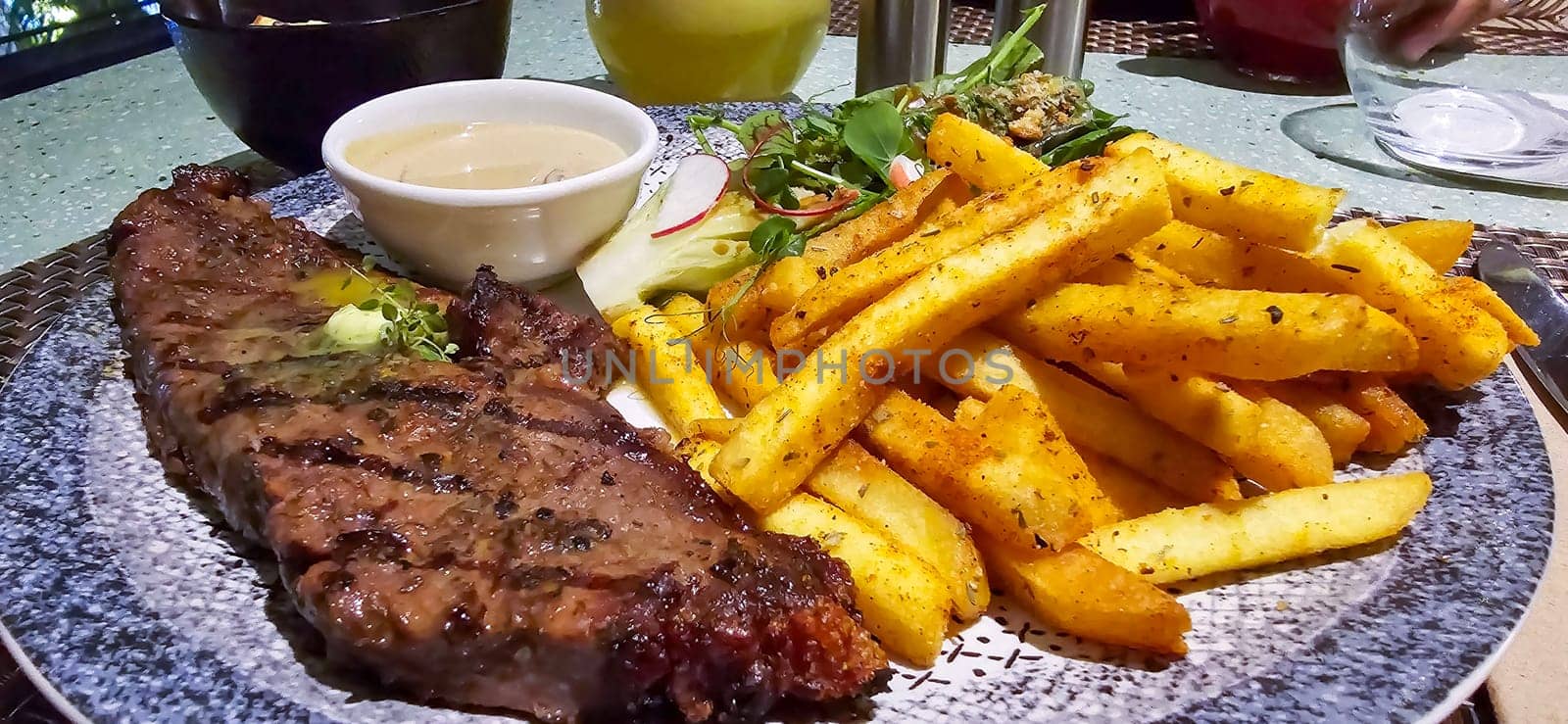 Beef New York strip loin steak or sirloin steak served with potatoes, and mushroom sauce and salad on plate by antoksena