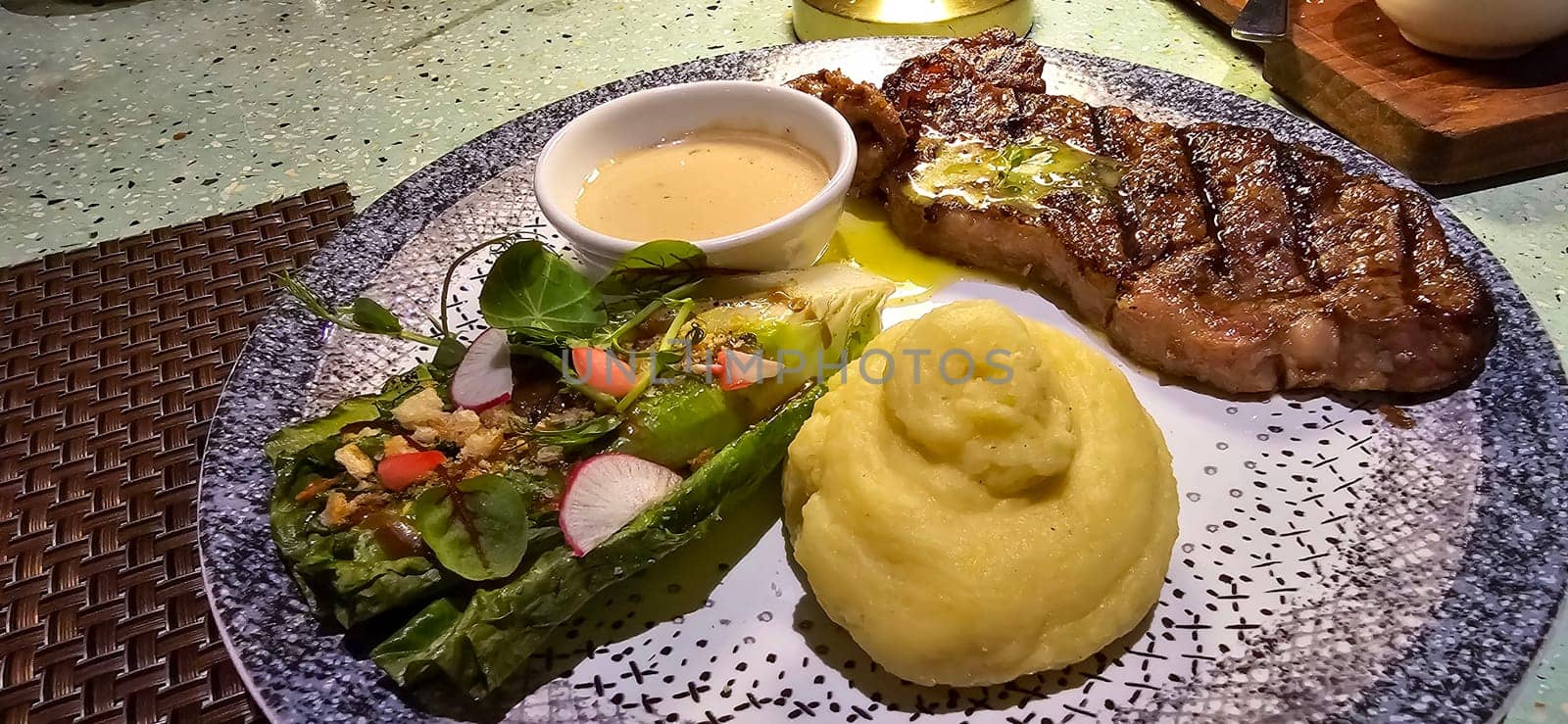 Beef New York strip loin steak or sirloin steak served with potatoes, and mushroom sauce and salad on plate Marble premium beef