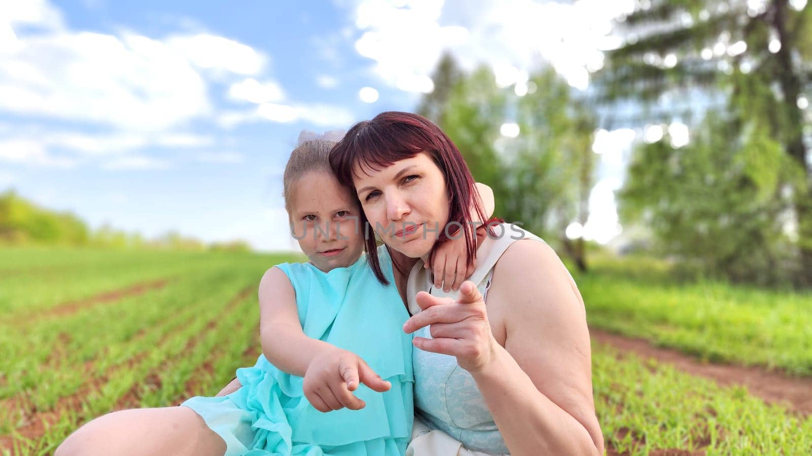 Happy mother and daughter enjoying rest, playing and fun on nature in green field. Woman and girl resting outdoors in summer or spring day