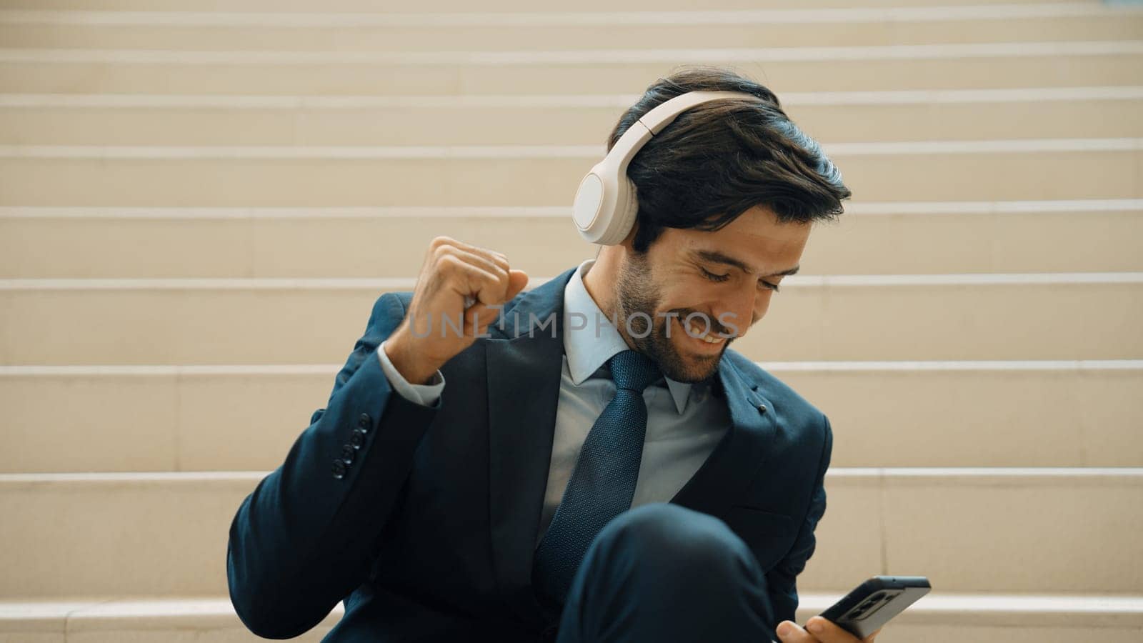 Closeup of smart business man listening and enjoy music while wear headphone. Project manager smiling while getting good news, getting promotion, increasing sales. Relaxing man enjoy music. Exultant.