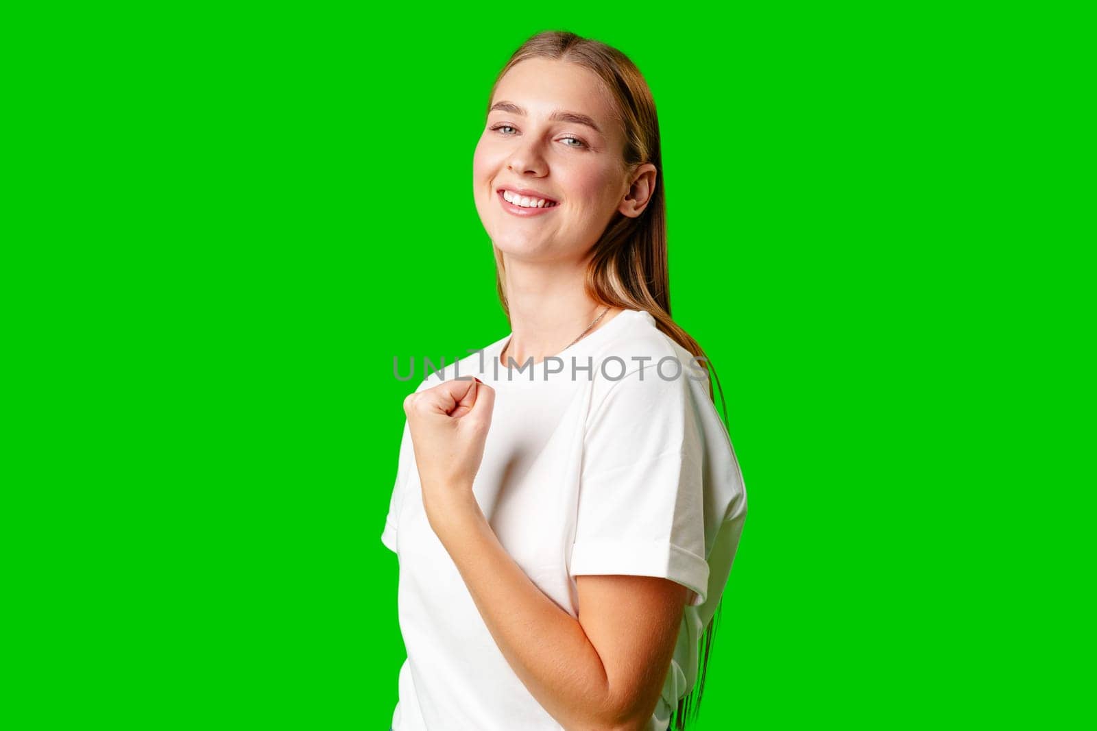 Happy Young Woman Raising Fists against green background in studio