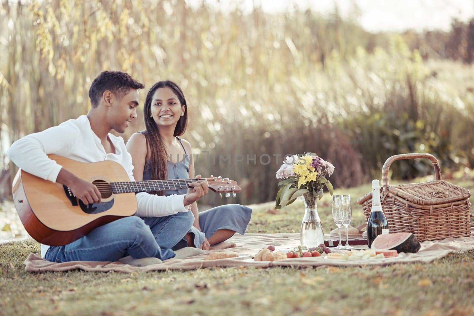 Man, woman and date with picnic, guitar and romance for love or relationship anniversary. Couple, nature and lake with music, happiness and summer passion with bouquet for valentines celebration.
